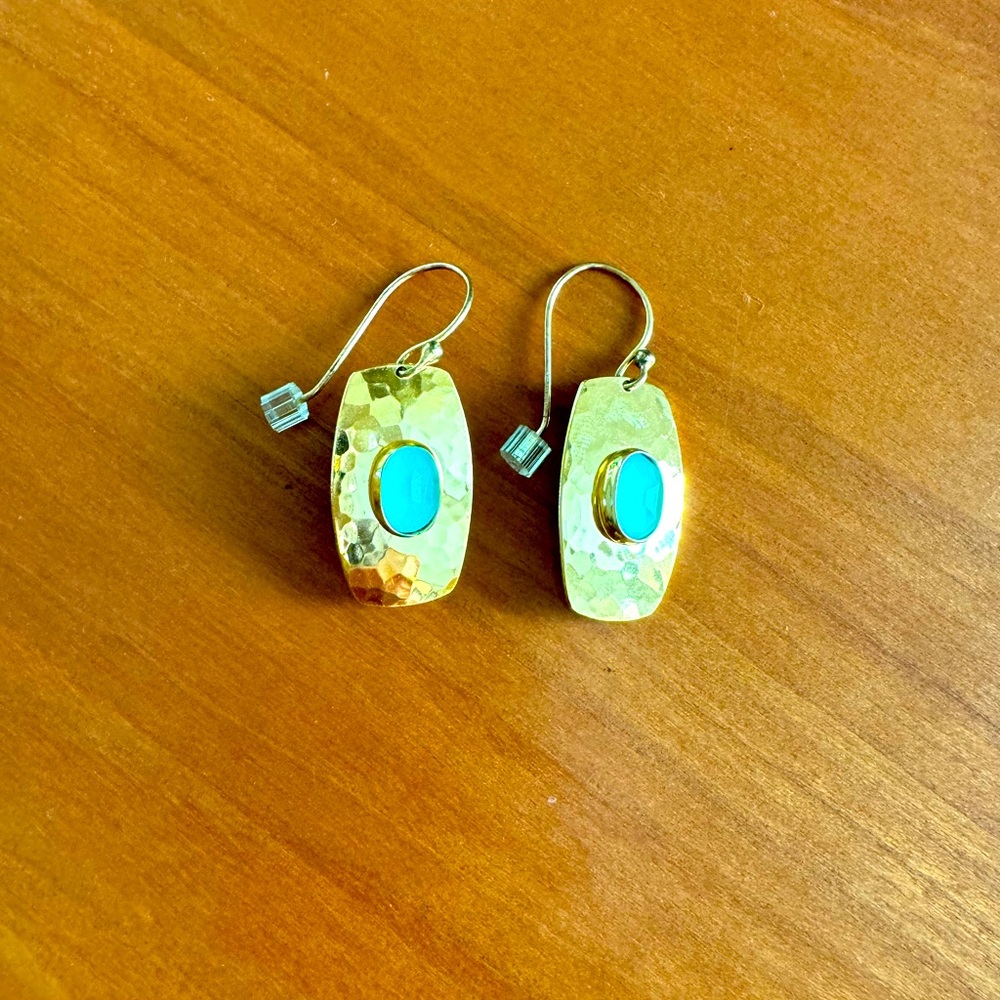 Sparkly gold shield style earring with green stone.